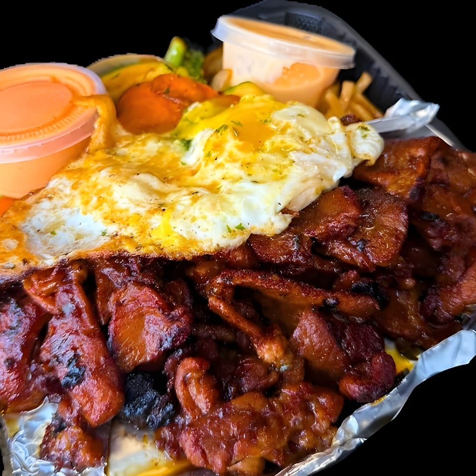 A takeout container filled with grilled chicken, a fried egg, vegetables, fries, and dipping sauces.